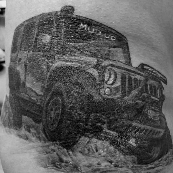 Realistic black and grey tattoo of a rugged Jeep driving through rough terrain, with "MUD UP" on the windshield, capturing an off-road adventure vibe.