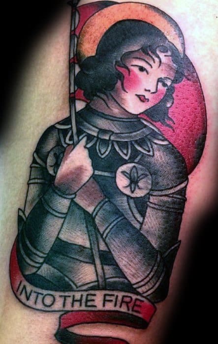 Traditional Joan of Arc tattoo with bold lines, red and black tones, holding a flag and a banner that reads “Into the Fire.”