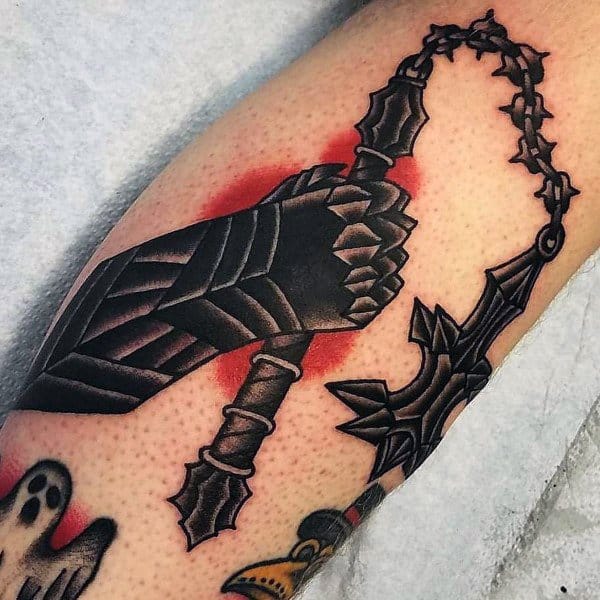 Bold mace tattoo featuring an armored hand gripping a spiked weapon with a barbed chain, accented by red shading, symbolizing strength and battle.