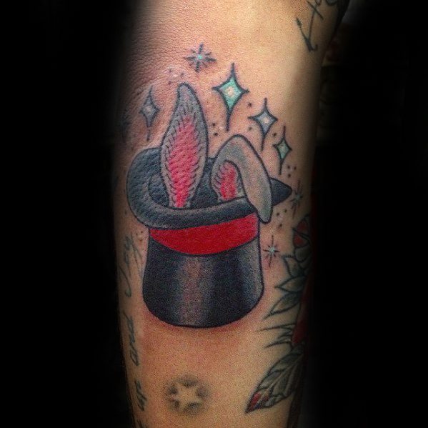 Tattoo of a rabbit's ears peeking out of a magician's hat, with stars in the background