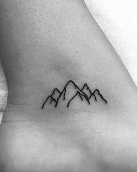 Minimalist mountain tattoo on the wrist, featuring simple fine lines forming sharp peaks for a subtle and elegant nature-inspired design.