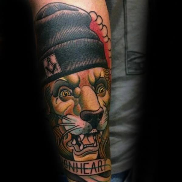 Neo-traditional lion tattoo with intense eyes, wearing a beanie and showing teeth, paired with the word “LIONHEART” for bold attitude.