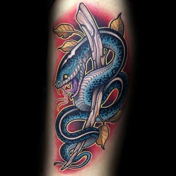 Neo-traditional tattoo of a fierce blue snake coiled around a branch, with sharp fangs, bold shading, and vibrant red accents for contrast.