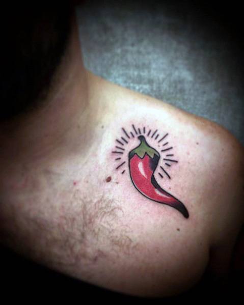 Bold red chili pepper tattoo on the chest with black outline shading and radiating lines, creating a striking and energetic design.