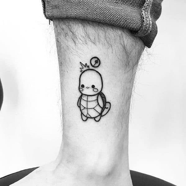 Minimalist Squirtle tattoo in black line art with a crown and tiny Pokeball above its head, placed on the ankle for a cute look.