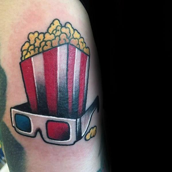 Tattoo of a popcorn bucket with classic red stripes paired with vintage 3D glasses, blending movie nostalgia and bold colors.