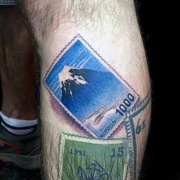 Colorful tattoo of a Japanese postage stamp featuring Mount Fuji and intricate details.