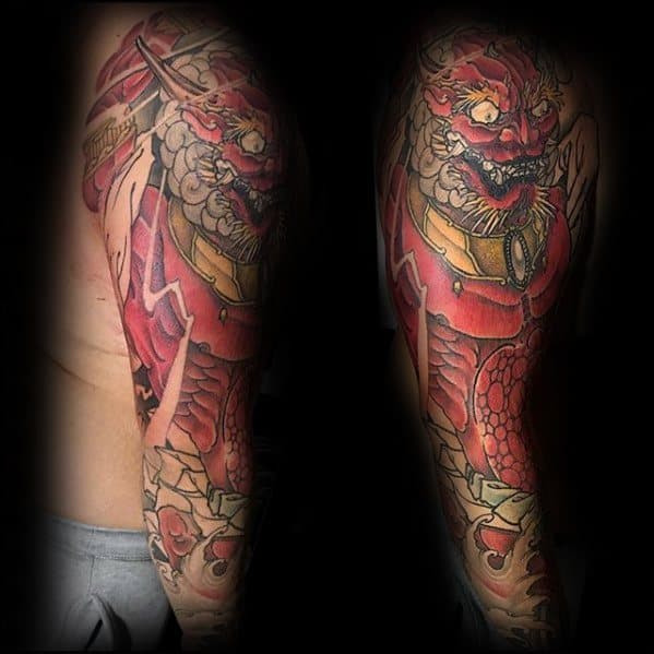 Fierce Raijin full sleeve tattoo with intense red thunder god, cracked earth effect, and golden drum details in traditional style.