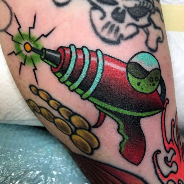 Bold and colorful ray gun tattoo with a classic retro sci-fi design, featuring bright red and green tones, glowing energy, and sleek details.