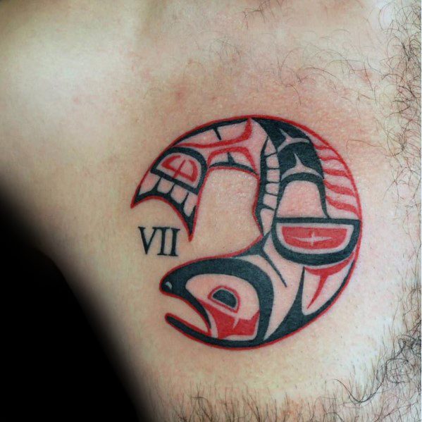 Tribal-style salmon tattoo in black and red, inspired by Indigenous art, forming a circular design with Roman numerals for a symbolic chest piece.
