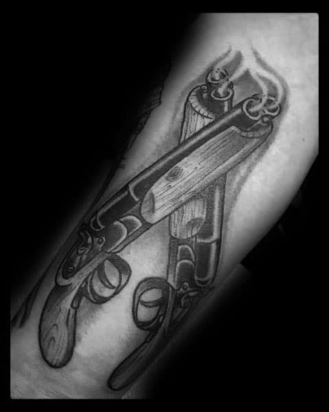 Black and grey tattoo of crossed smoking shotguns with intricate wood and metal detailing, creating a bold and powerful design.