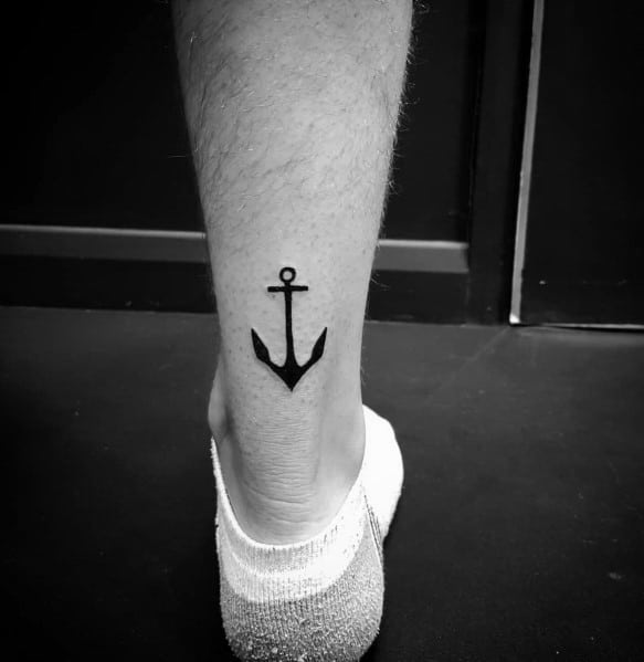 Minimalist black anchor tattoo on the lower leg, featuring clean lines and a simple design, symbolizing stability, strength, and grounding.
