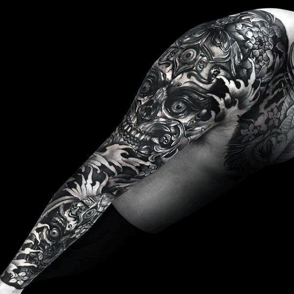Dark Tibetan skull full sleeve tattoo in black and grey with intense shading, multiple skull faces, and swirling smoke effects.