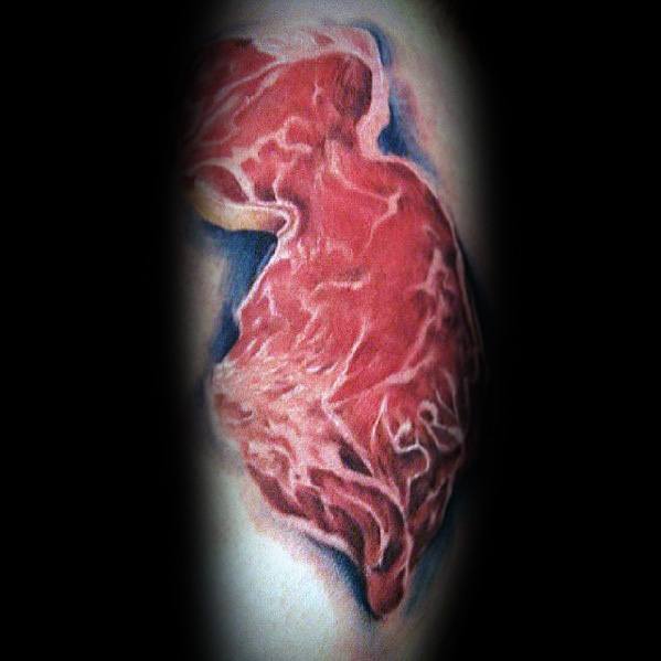 Tattoo of a raw steak with realistic marbling and shading, featuring subtle blue tones for depth, creating a bold and lifelike meat-inspired design
