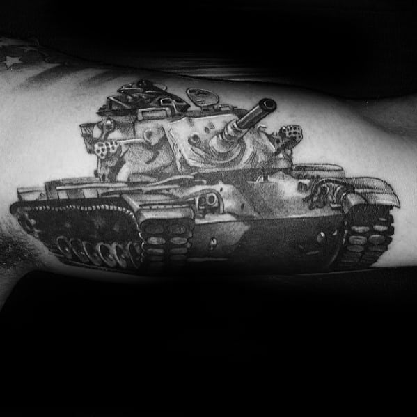 Highly detailed black and grey tattoo of a modern tank on the bicep, with bold shadows and a strong frontal perspective.