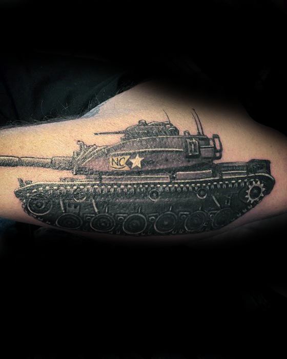 Black and grey tattoo of a side-view military tank with “NC” and a star insignia, detailed treads, and a realistic worn-metal texture.
