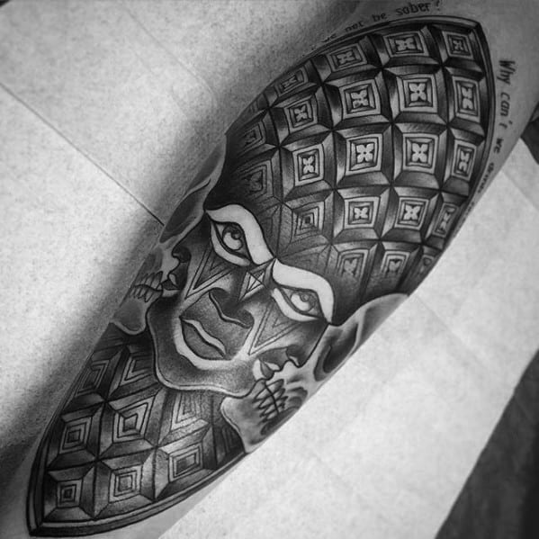 Black and grey Tool-inspired tattoo with a geometric face design, skull details, and repeating 3D cube patterns across the head.