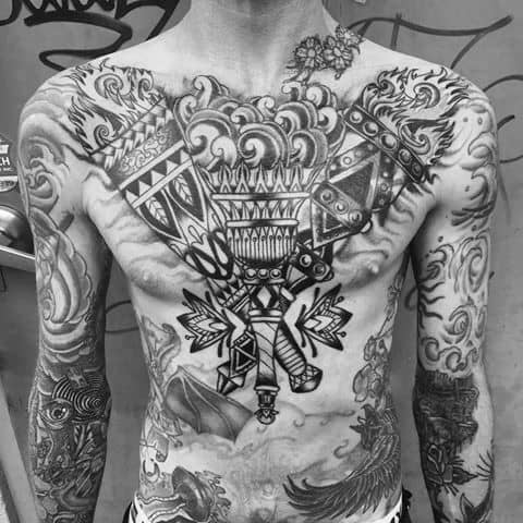 Full chest and torso torch tattoo with heavy blackwork, tribal patterns, clouds, and symmetrical ornamental elements extending across the body.
