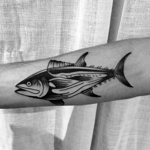 Black and grey tuna fish anatomy tattoo on a man's forearm, featuring bold outlines and intricate shading for a detailed skeletal design.
