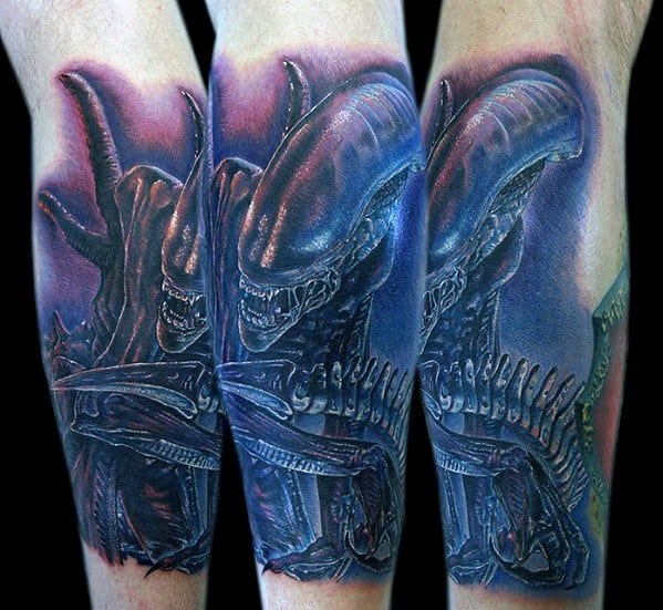 Vibrant Xenomorph tattoo with blue and purple tones, showcasing the creature’s menacing face and ribbed exoskeleton in high detail.