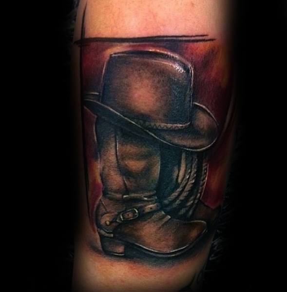 Tattoo of a cowboy boot with a hat and lasso, featuring rich shading and a bold Western aesthetic, symbolizing cowboy heritage and rugged spirit.