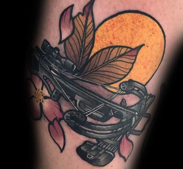 Color tattoo of a detailed crossbow overlaid with pink flowers and autumn leaves, set against a bold orange sun backdrop.