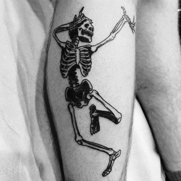 Dancing skeleton tattoo with bold black ink, raised arms, and a playful pose, creating a lively and expressive design on the leg.