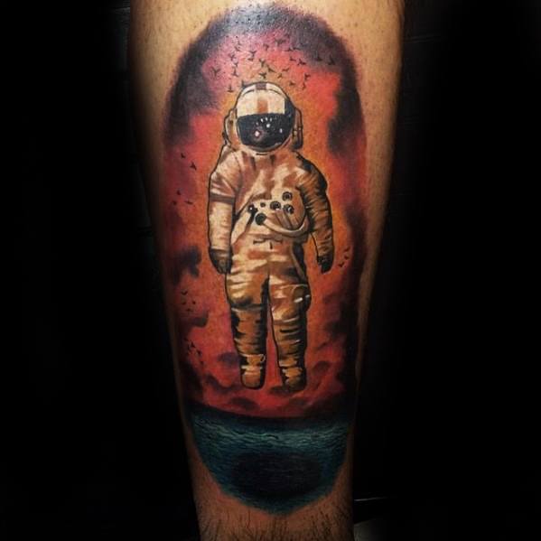 Dark-themed Deja Entendu astronaut tattoo with a fiery red sky, flock of black birds, and a moody teal ocean beneath.