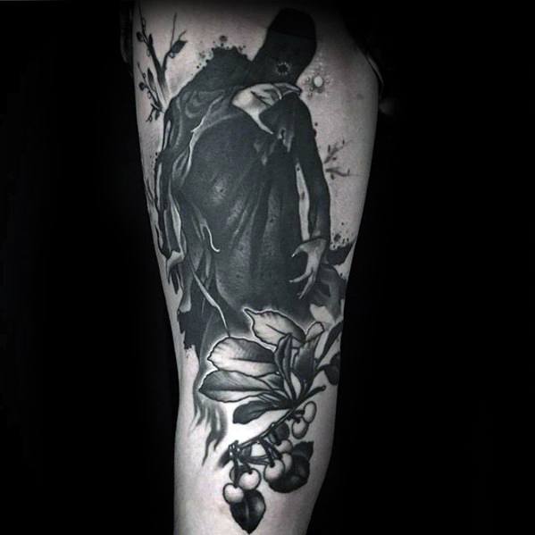 Dark thigh tattoo of a shadowy Dementor figure hovering above detailed flowers and berries, blending nature with haunting fantasy.