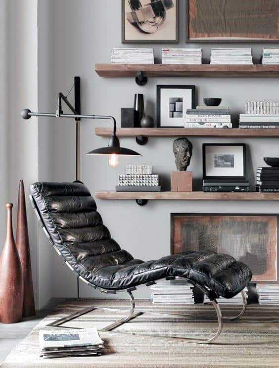 Elegant black leather chair in office space with floating shelves and modern decor.
