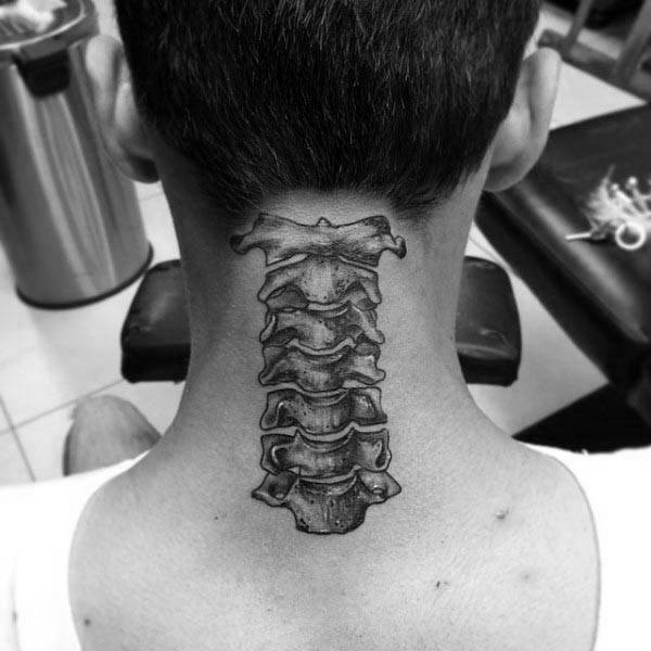 Black and grey tattoo of cervical vertebrae on the back of the neck, detailed with realistic bone texture and shading.
