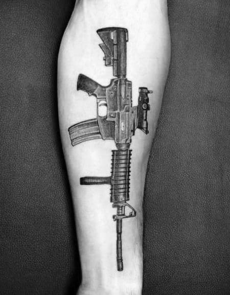 Realistic black and grey AR-15 tattoo on the forearm, showcasing intricate details of the rifle with a tactical grip and magazine.