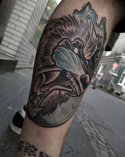 Dark-themed baboon tattoo with bold shading, fierce expression, and glowing blue facial accents, creating a striking and intense leg design.