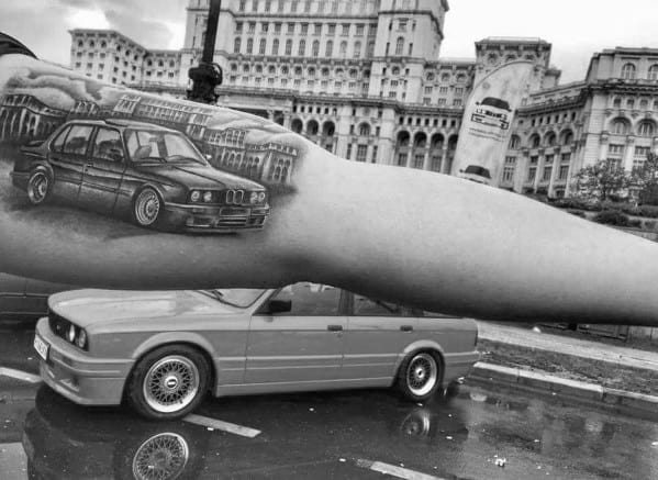 Detailed BMW E30 touring tattoo on forearm, featuring realistic shading and perspective for a striking automotive-inspired design.