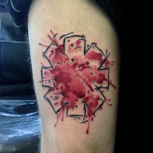 Thigh tattoo featuring the Red Hot Chili Peppers logo with a splattered watercolor effect and abstract black line details for a bold artistic look.