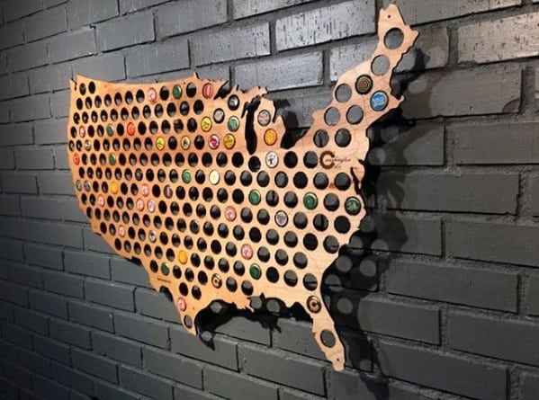 Wooden USA map on a brick wall, filled with bottle caps in each state outline