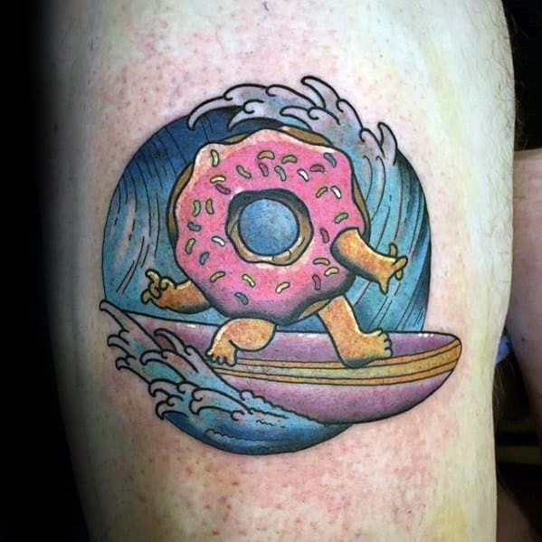 Tattoo of a pink frosted donut with arms and legs surfing a wave, blending beach vibes with playful cartoon fun.