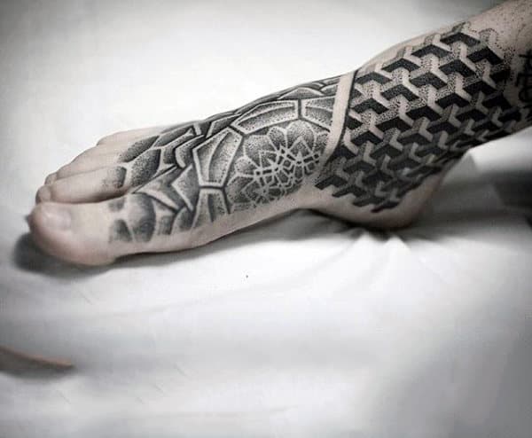 A foot with an intricate black geometric tattoo featuring hexagonal and grid patterns covering the top and side