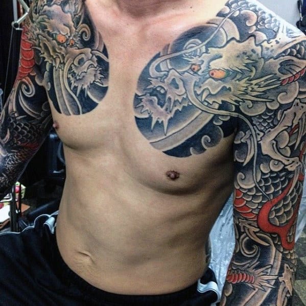 Tattooed man with detailed dragon designs across chest and sleeves