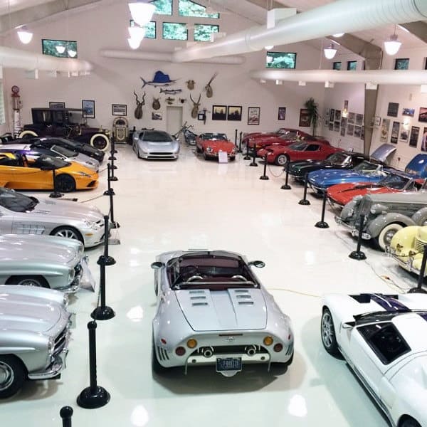 A museum-style garage with classic and modern cars on pristine white floors.