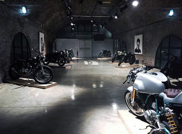 Minimalist brick-walled motorcycle garage with vintage bikes.