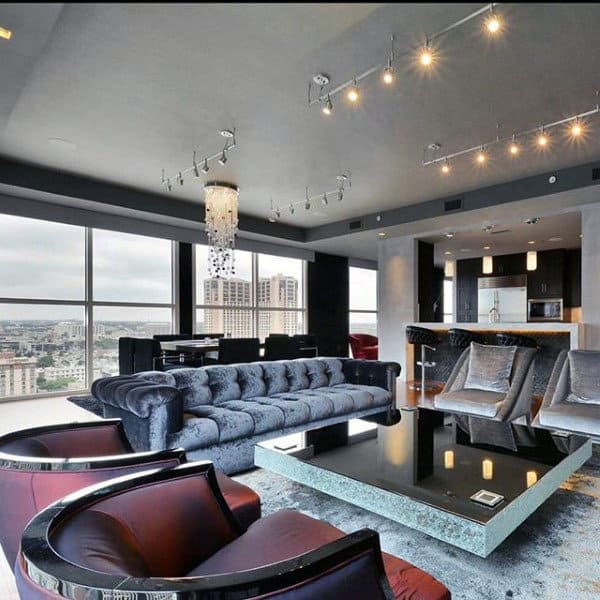 Elegant bachelor pad living room with plush velvet sofa, modern lighting, and city views.