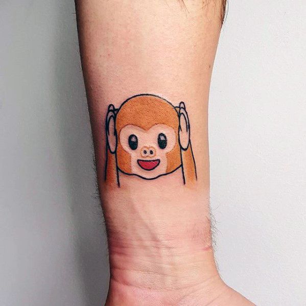 Tattoo of a cartoon monkey emoji covering its ears on a person's arm