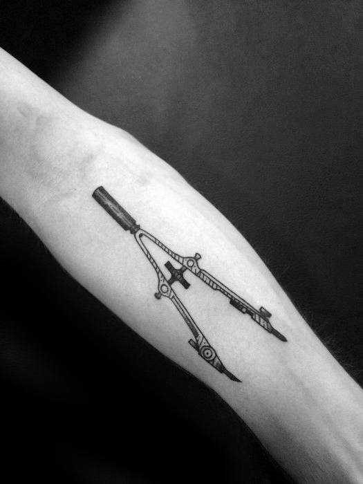 Tattoo of a finely detailed drawing compass on the forearm, symbolizing precision, design, and geometry with a clean black-ink style.