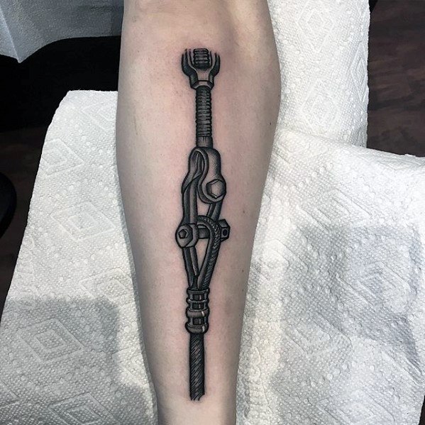 Tattoo of a realistic turnbuckle and cable on the forearm, shaded in black and gray to emphasize mechanical detail and industrial strength.