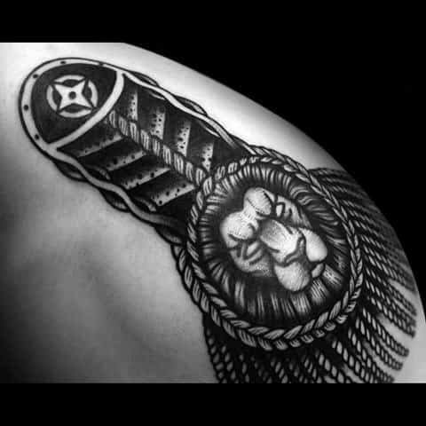 Bold epaulette tattoo with a detailed lion face at the center, braided edging, and textured tassels draping over the shoulder.