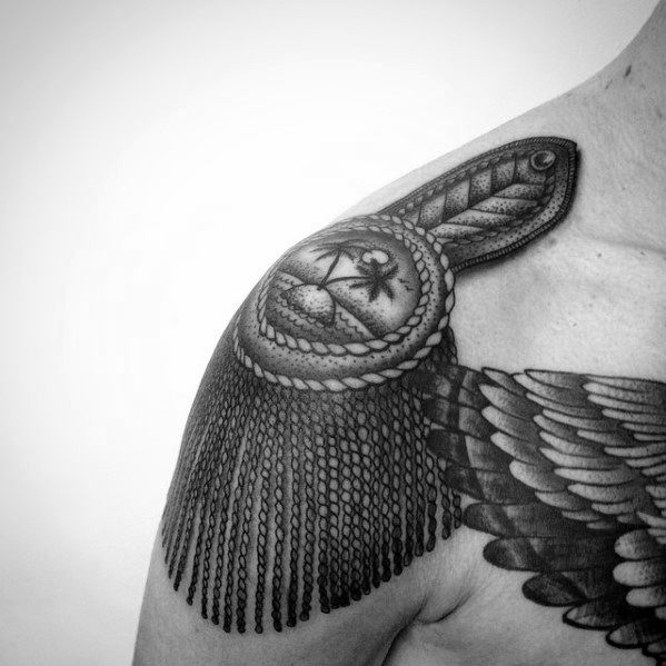 Epaulette tattoo with a palm tree and moon emblem, rope border, and long twisted tassels flowing over the shoulder.