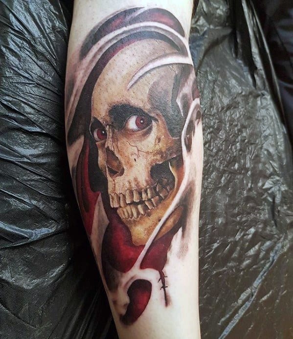 Realistic Evil Dead tattoo of a grinning skull peeking through torn flesh with eerie red eyes and deep red shadows, evoking classic horror vibes