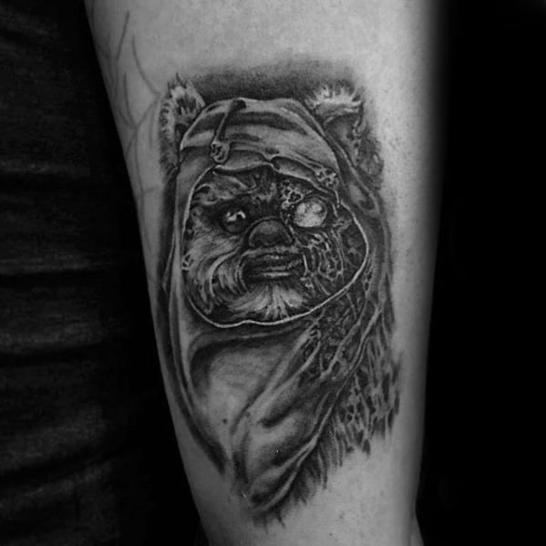 Dark and gritty black and grey Ewok tattoo with a torn hood and intense expression, blending realism with a slightly decayed texture.