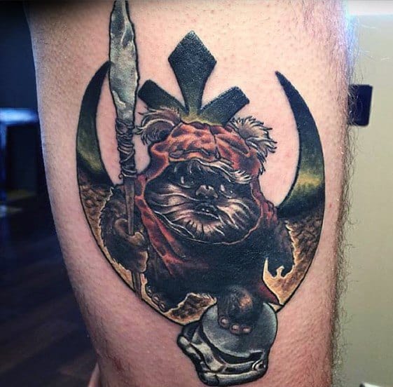 Powerful Ewok tattoo standing on a Stormtrooper helmet, gripping a spear, with the Rebel Alliance symbol forming the background.